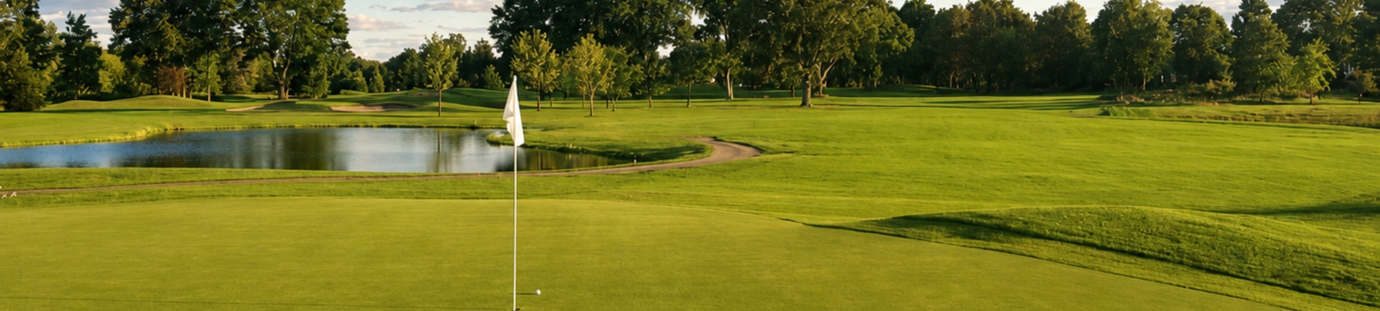 Golf course green with a flagstick beside a pond